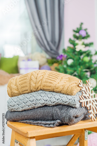 Stack of white cozy knitted sweaters on a wooden table