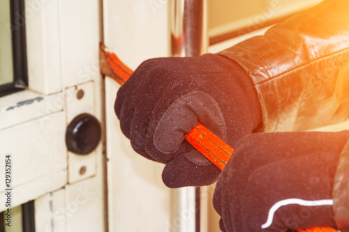Fotografie Burglar wearing leather coat breaking in a house
