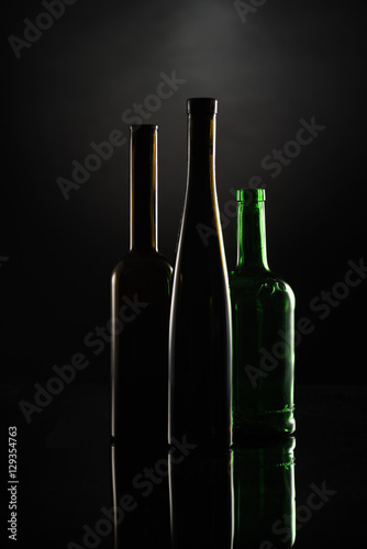 silhuettes of dark wine bottles on the black backgound contoured by the light