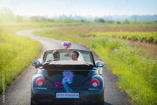 Newlyweds in a car on a country road. just Married on the back photo