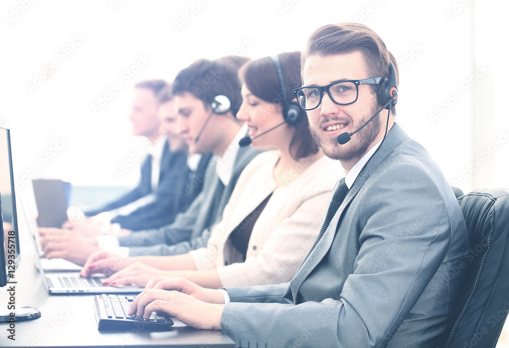 Attractive young man working in a call center with his colleagues Attractive young man working in a call center with his colleagues
