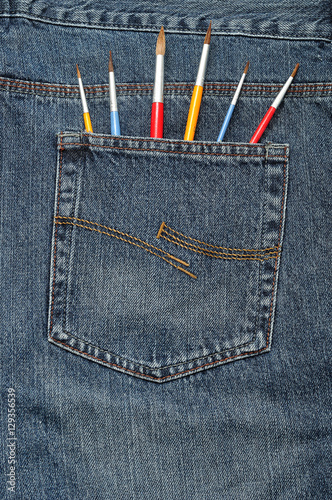 Paint brushes sticking out of a back pocket of a denim jean