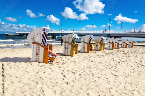 Beautiful sandy beach full of wicker chairs against blue sky