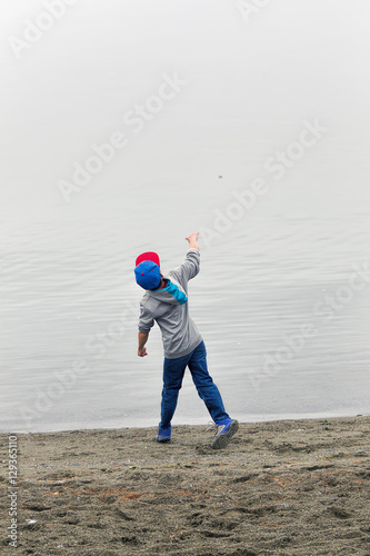 Boy throws rock in water.