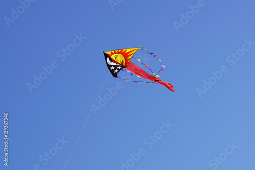 Colorful kite flying in the blue sky with wind.