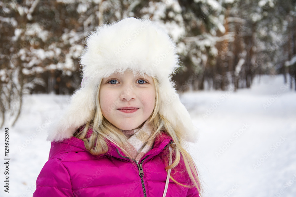 In winter, snow-covered pine forest plays a beautiful little gir