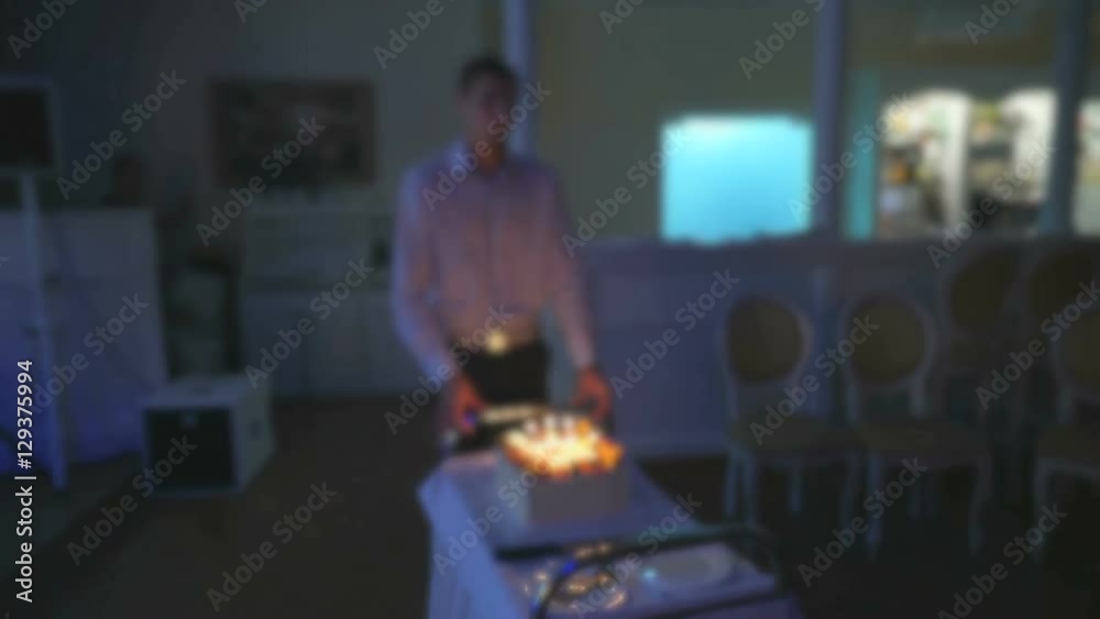 A waiter bringing birthday cake in the restaurant hall A waiter bringing birthday cake in the restaurant hall