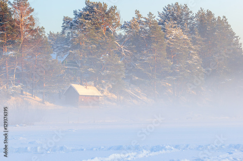 Country sauna and a winter fog over the frozen river.