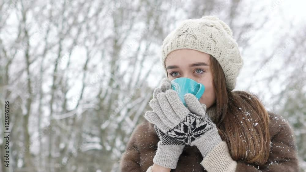 Pretty girl drinking a cup of hot beverage outdoor in winter day Pretty girl drinking a cup of hot beverage outdoor in winter day