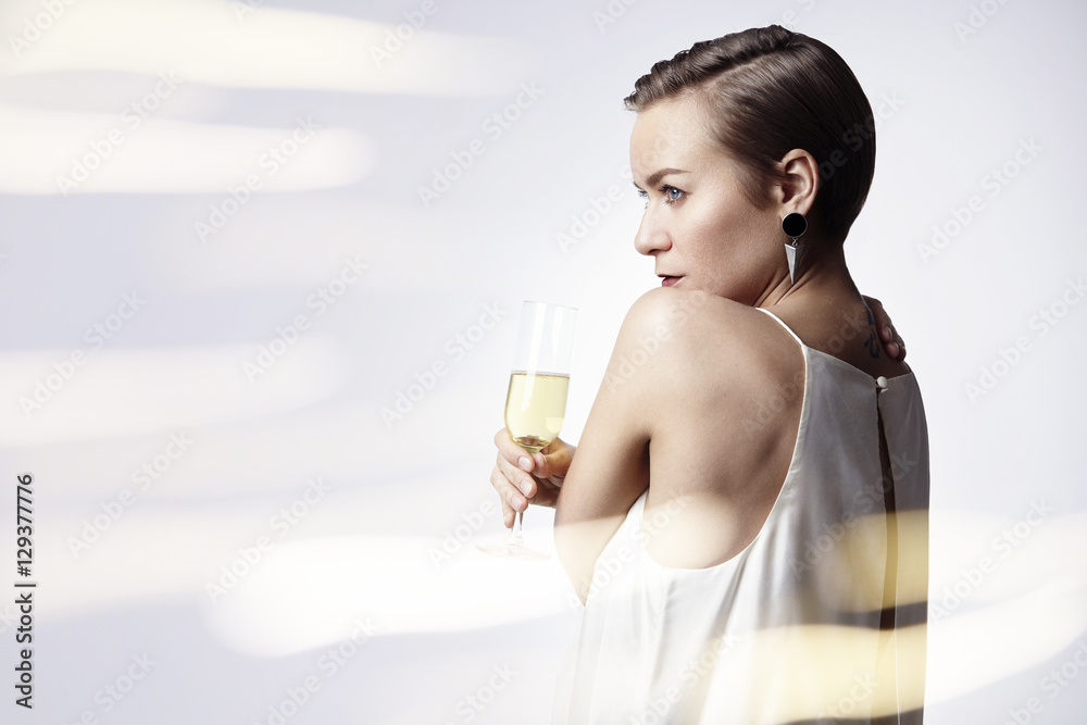 Young woman is celebrating with glass of champagne. Flares on background. Party, New Year, Christmas concept Young woman is celebrating with glass of champagne. Flares on background. Party, New Year, Christmas concept