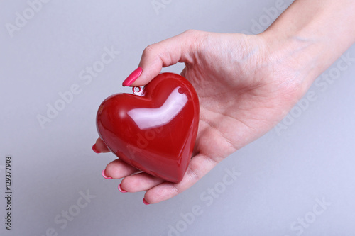 doctor with stethoscope examining red heart, isolated on white