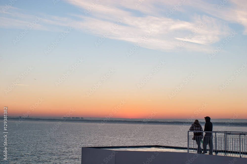 Silhouette of couple watching sunset from ferry crossing the Strait of Dover