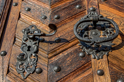 Old metal handle with knocker on a wooden door