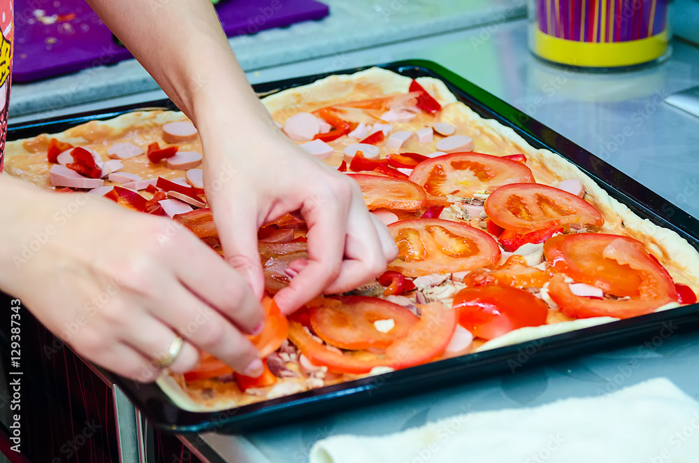 Woman hands grating cheese on the pizza. Young woman preparing the pizza in the kitchen.