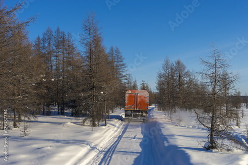 Winter landscape with forest, snow and ice road and SUV truck. photo