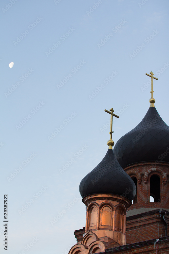 Bell tower of old believer orthodox church at early winter morning, crosses with moon in the sky