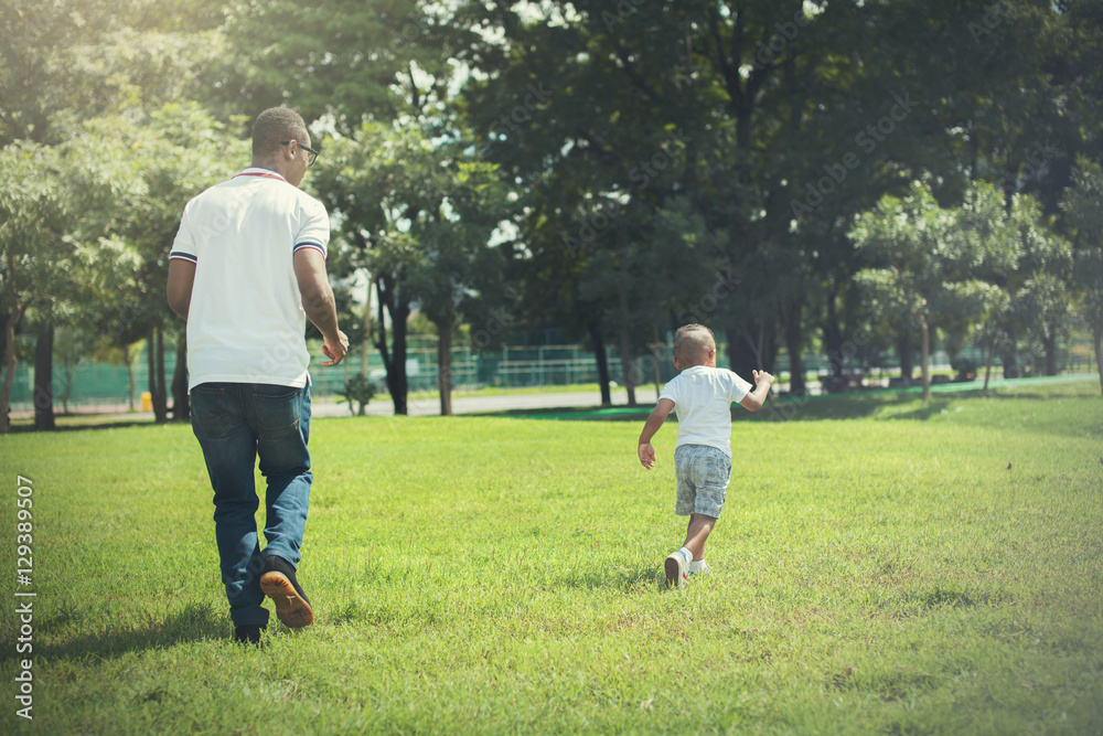 Father and son running and chasing each other in green park Father and son running and chasing each other in green park