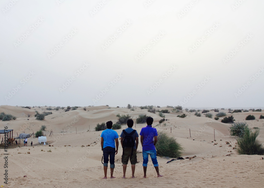 A group of 3 young Indian men watching the sunset at a desert safari camp in Dubai, UAE