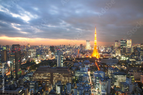 Illuminated Tokyo Tower amidst cityscape with sunset sky