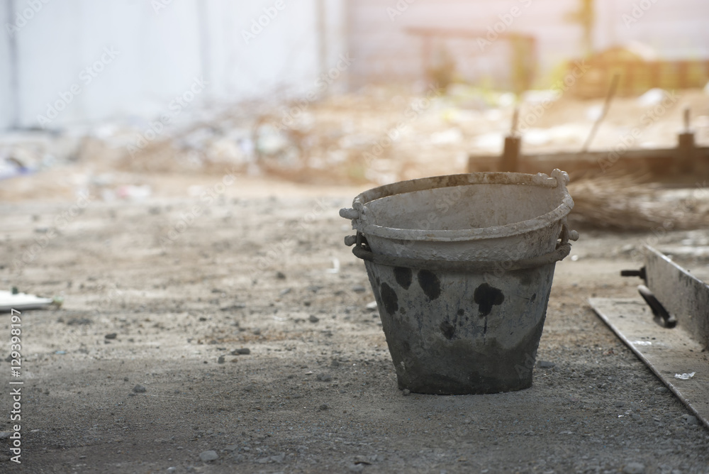 Old cement mixer bucket placed on a cement floor in the construction site.