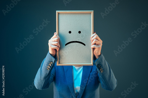 Businesswoman is pessimistic, holding smiley emoticon over face