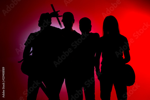 Band of young male musicians standing with instruments on a red background