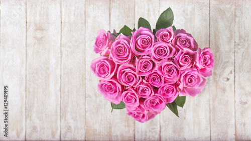 Beautiful bouquet of pink roses in heart shape on wooden backgro