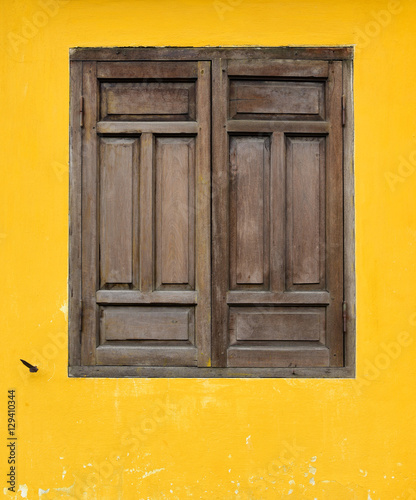 Brown wooden window on yellow wall in Hoi An