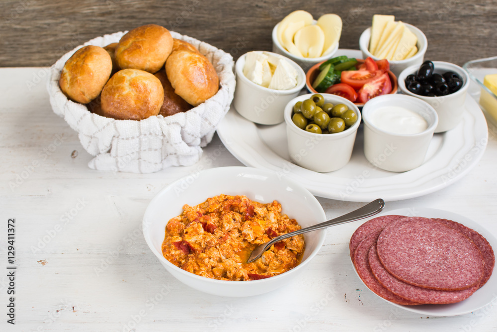 Traditional Turkish breakfast: egg, toast, pogaca pasties, vegetables, cheeses, olives and halal turkey salami, selective focus; copy space for text