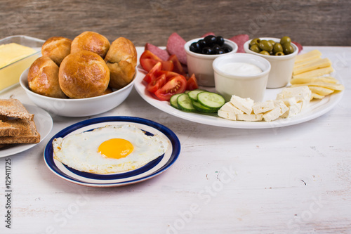 Traditional Turkish breakfast: egg, toast, pogaca pasties, vegetables, cheeses, olives and halal turkey salami, selective focus; copy space for text
