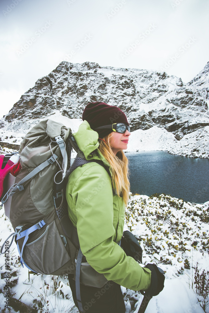 Woman backpacker hiking Travel Lifestyle adventure concept snow rocky mountains and lake on background winter vacations