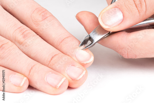 Fotografi master of manicure cuts off the cuticle from the client fingers in nail salon