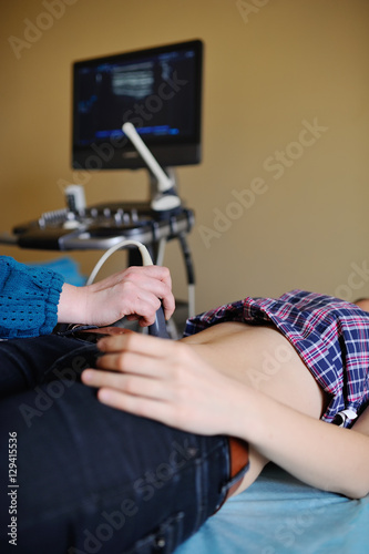 Doctor makes the patient women abdominal ultrasound. Pregnancy. Ultrasound Scanner in the hands of a doctor. Diagnostics. Sonography.Abdominal ultrasound