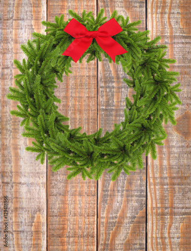 Christmas wreath with red bow on the wooden background