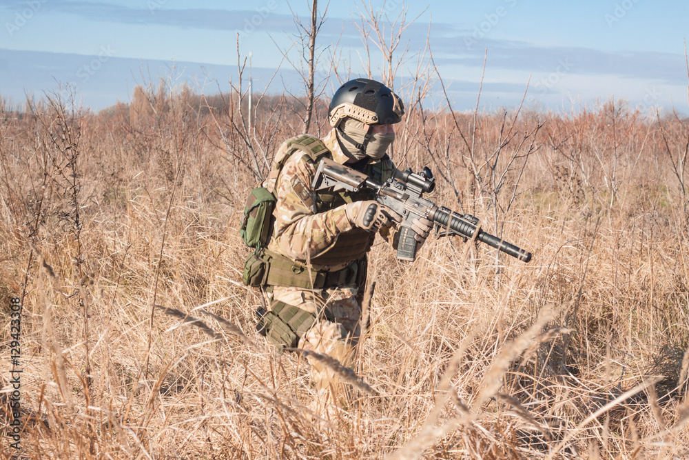 Fototapeta premium aiming, airsoft player with gun, helmet and bulletproof vest running in fields