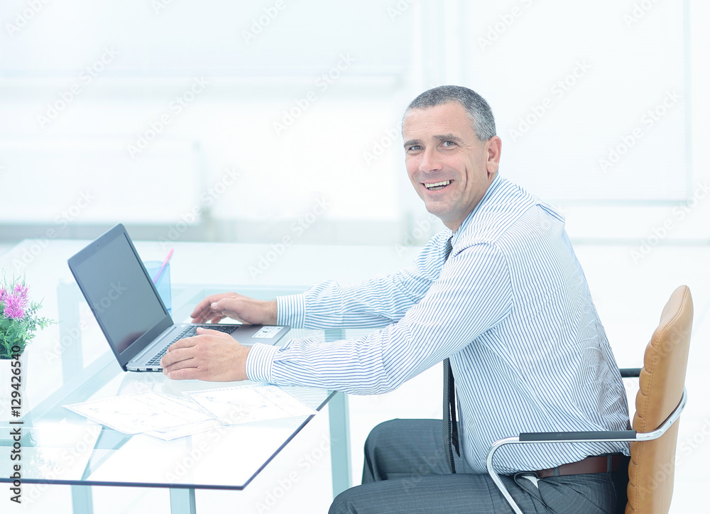 successful smiling businessman working on laptop at Desk in offi successful smiling businessman working on laptop at Desk in offi