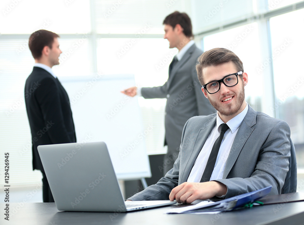Portrait of a handsome young business man with people in background at office meeting