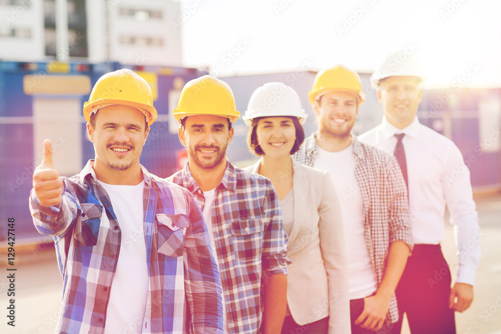 group of smiling builders in hardhats outdoors group of smiling builders in hardhats outdoors