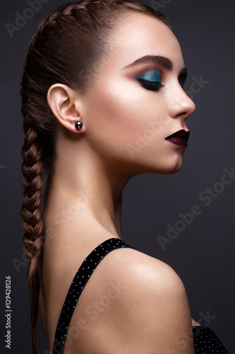 Beautiful woman with bright creative make-up. Model with braids and lip color marsala. Beauty face. The photo was taken in a studio.