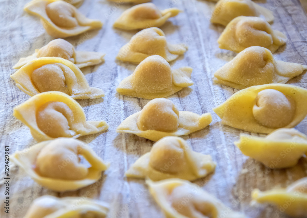 Raw italian cappelletti, fresh homemade pasta stuffed with cheese and meat on rustic wood table. Natural light. Raw italian cappelletti, fresh homemade pasta stuffed with cheese and meat on rustic wood table. Natural light.