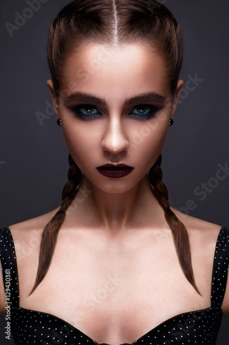 Beautiful woman with bright creative make-up. Model with braids and lip color marsala. Beauty face. The photo was taken in a studio.
