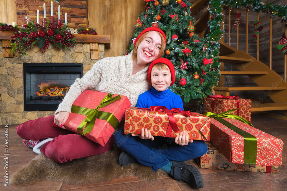  Young happy woman and kid  sitting on the floor with gift boxes. Merry Christmas concept.