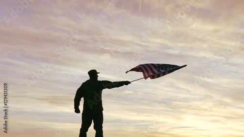 4K. Soldier silhouette waves American Flag, sunrise time  
