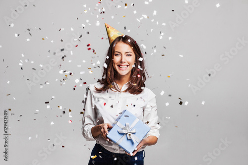 Konstfotografi Beautiful happy woman with gift box at celebration party with confetti falling everywhere on her