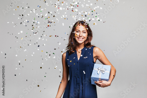 Canvas Print Beautiful happy woman with gift box at celebration party with confetti falling everywhere on her