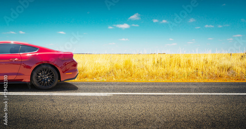 Sport car .parked on road side with field of golden wheat background .