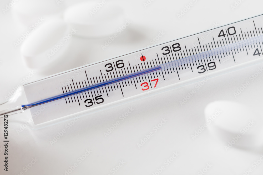 Foto Stock Termometro che mostra temperatura corporea di 37,5 gradi  centigradi con pillole bianche | Adobe Stock