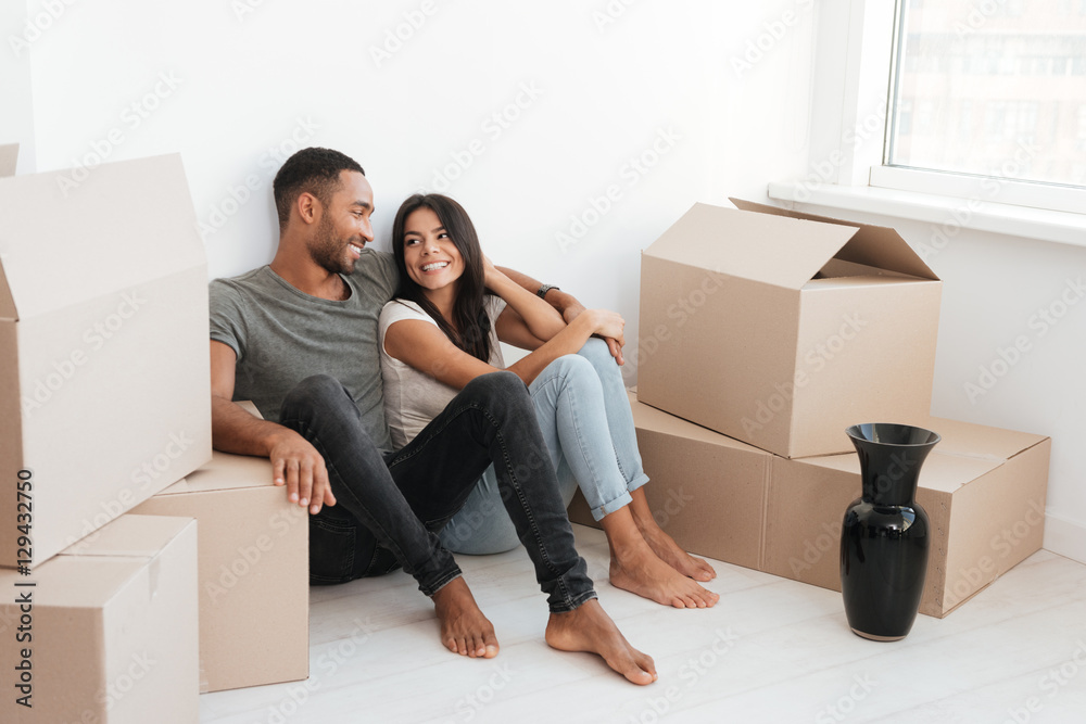 Cheerful couple lying on floor with unpacked boxes Cheerful couple lying on floor with unpacked boxes
