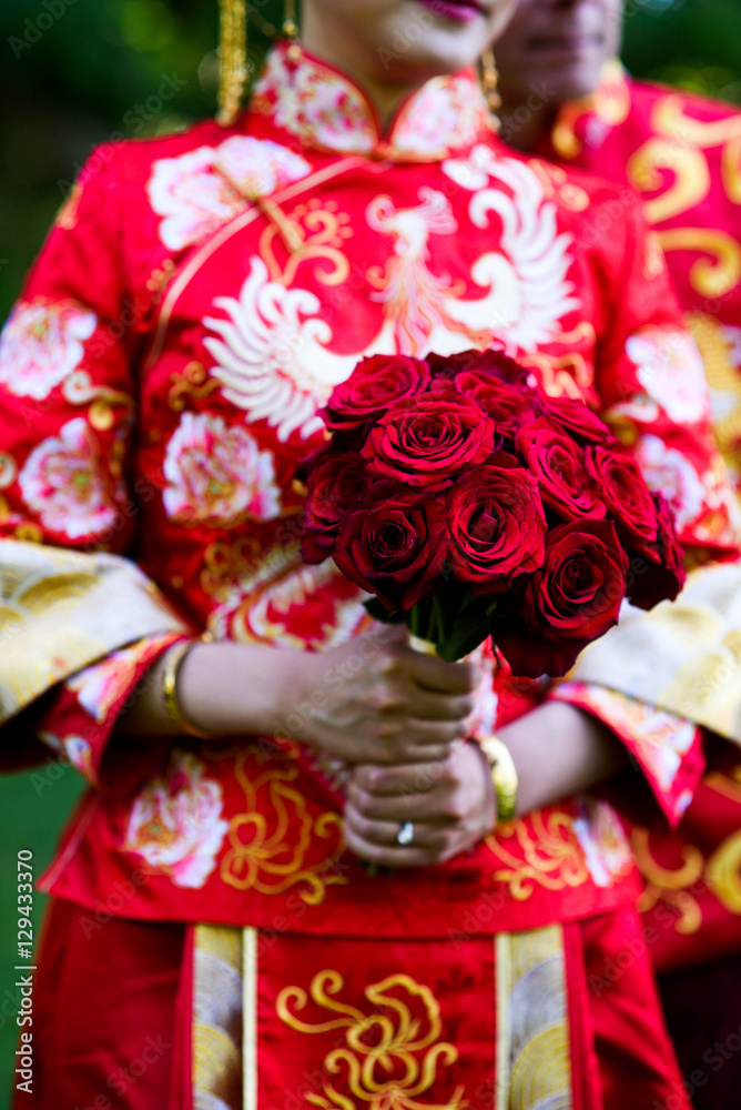Woman in Chinese national clothes holds bouquet of red roses Woman in Chinese national clothes holds bouquet of red roses