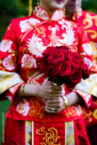 Woman in Chinese national clothes holds bouquet of red roses